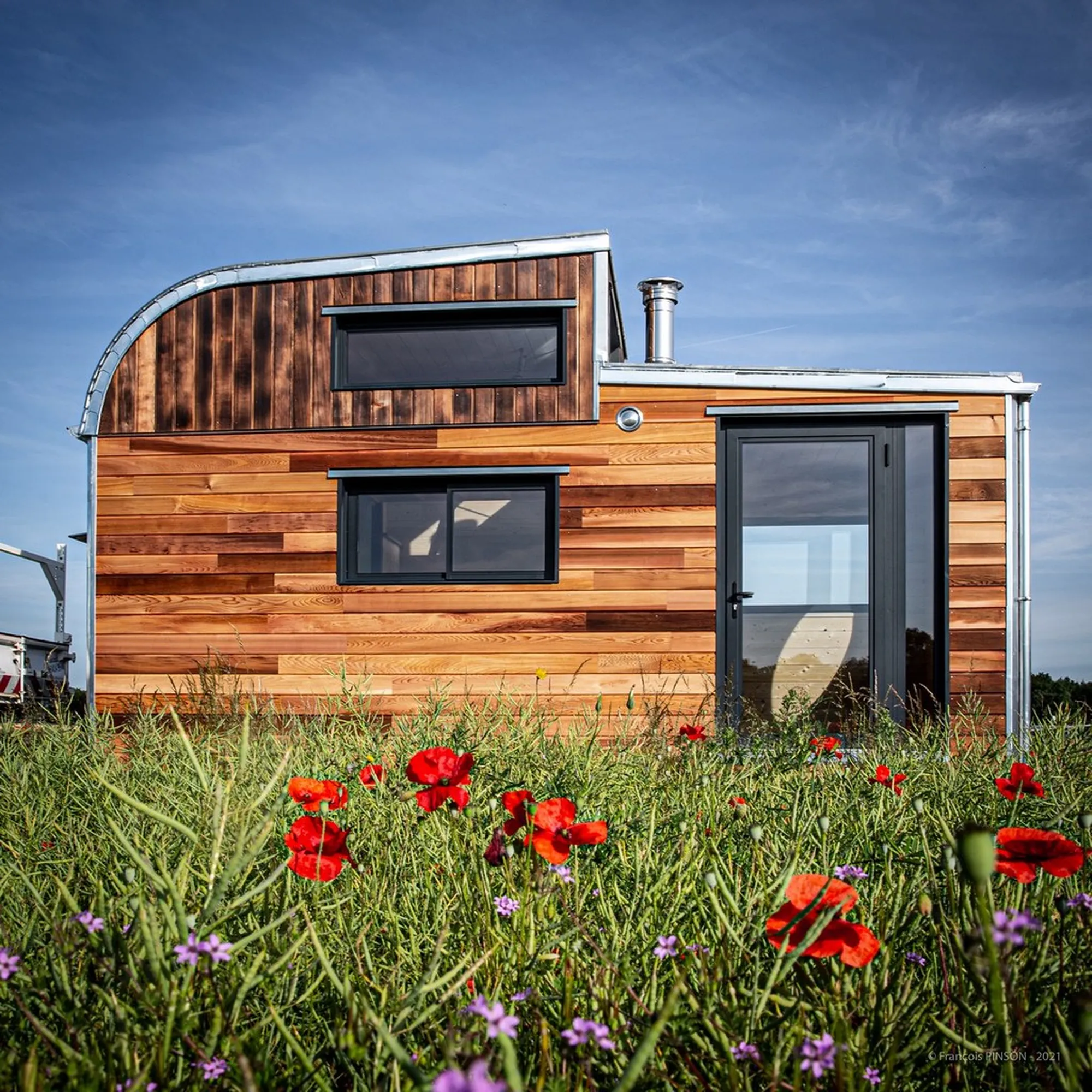 Tiny house en bois située au milieu d’un champ.