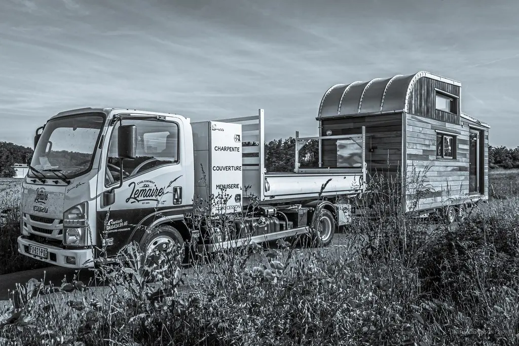 Tiny house tirée par camion, petite maison mobile montée sur remorque, conçue pour être transportée facilement tout en offrant un habitat confortable et fonctionnel.